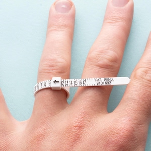 May include: White plastic ring sizer with a black arrow and numbers from 6 to 17. The text "PAT. PEND. 9101693" is printed on the sizer.