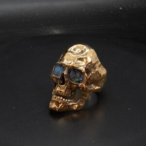 golden skull ring based on argus panoptes the greek one hundred eyed cyclops crushed opal set eyes three quarter front view