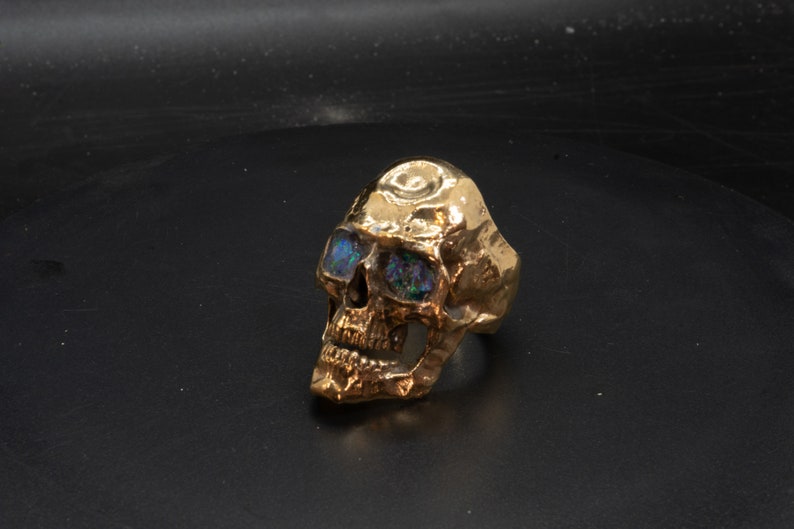 golden skull ring based on argus panoptes the greek one hundred eyed cyclops crushed opal set eyes three quarter front view