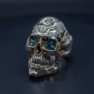 silver skull ring based on argus panoptes the greek one hundred eyed cyclops crushed opal set eyes three quarter front view