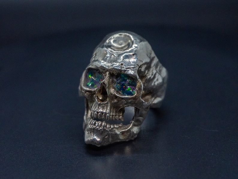 silver skull ring based on argus panoptes the greek one hundred eyed cyclops crushed opal set eyes three quarter front view