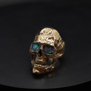 golden skull ring based on argus panoptes the greek one hundred eyed cyclops crushed opal set eyes front right view