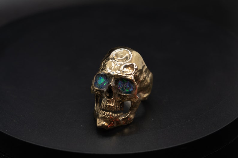 golden skull ring based on argus panoptes the greek one hundred eyed cyclops crushed opal set eyes front right view