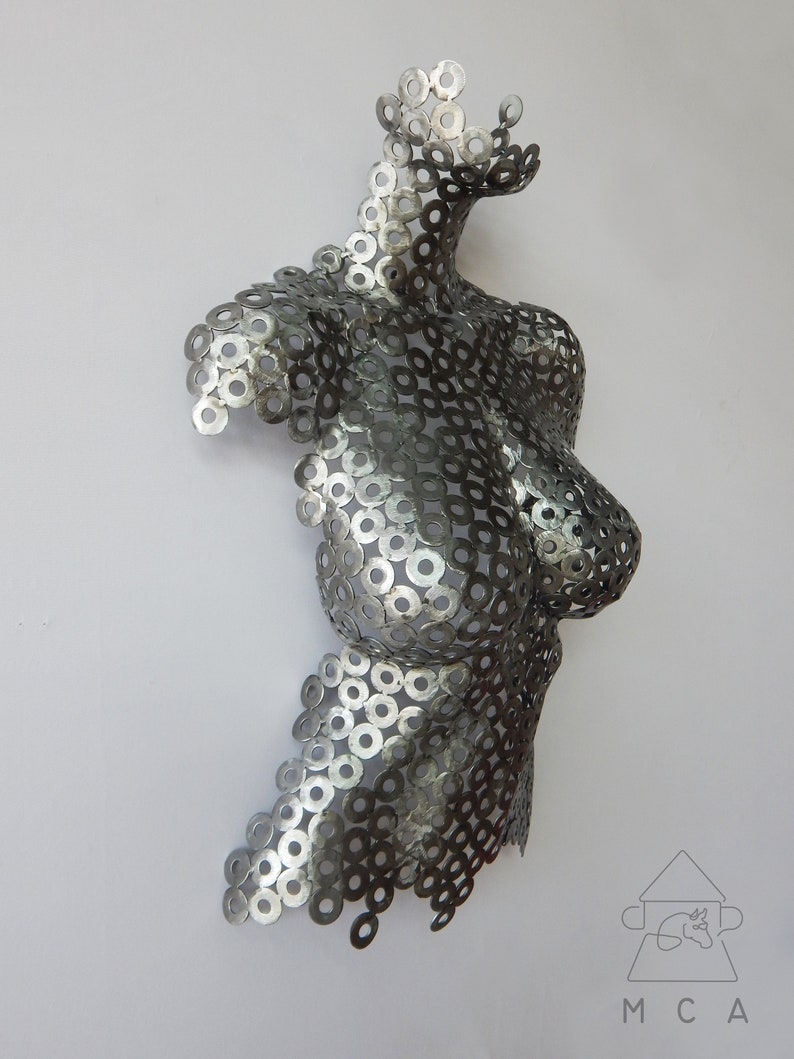 May include: A silver metal sculpture of a torso made from hundreds of small metal washers. The sculpture is abstract and has a modern design.