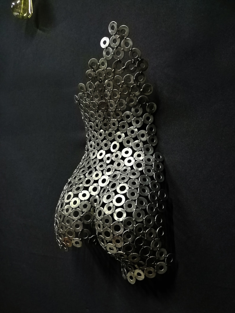 May include: A silver metal sculpture of a human torso made from a collection of small, round metal washers.