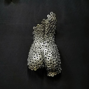 May include: A silver metal sculpture of a human torso made from a collection of metal washers.