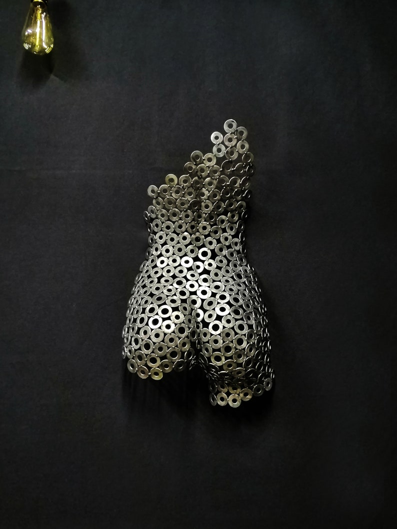 May include: A silver metal sculpture of a human torso made from a collection of metal washers.