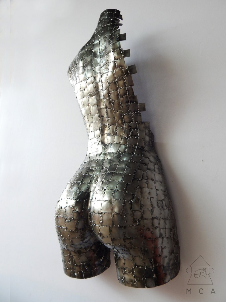 This photograph shows a metal sculpture with a female figure, made with hundreds of pieces of metal sheet that each do not exceed one inch in size, welded one by one until forming the beautiful hips of a woman and part of your back