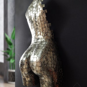 This photograph shows a metal sculpture with a female figure, made with hundreds of pieces of metal sheet that each do not exceed one inch in size, welded one by one until forming the beautiful hips of a woman and part of your back