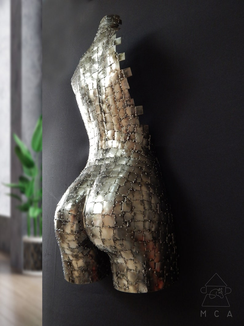 This photograph shows a metal sculpture with a female figure, made with hundreds of pieces of metal sheet that each do not exceed one inch in size, welded one by one until forming the beautiful hips of a woman and part of your back