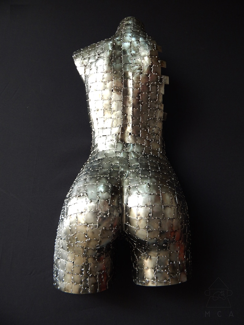 This photograph shows a metal sculpture with a female figure, made with hundreds of pieces of metal sheet that each do not exceed one inch in size, welded one by one until forming the beautiful hips of a woman and part of your back