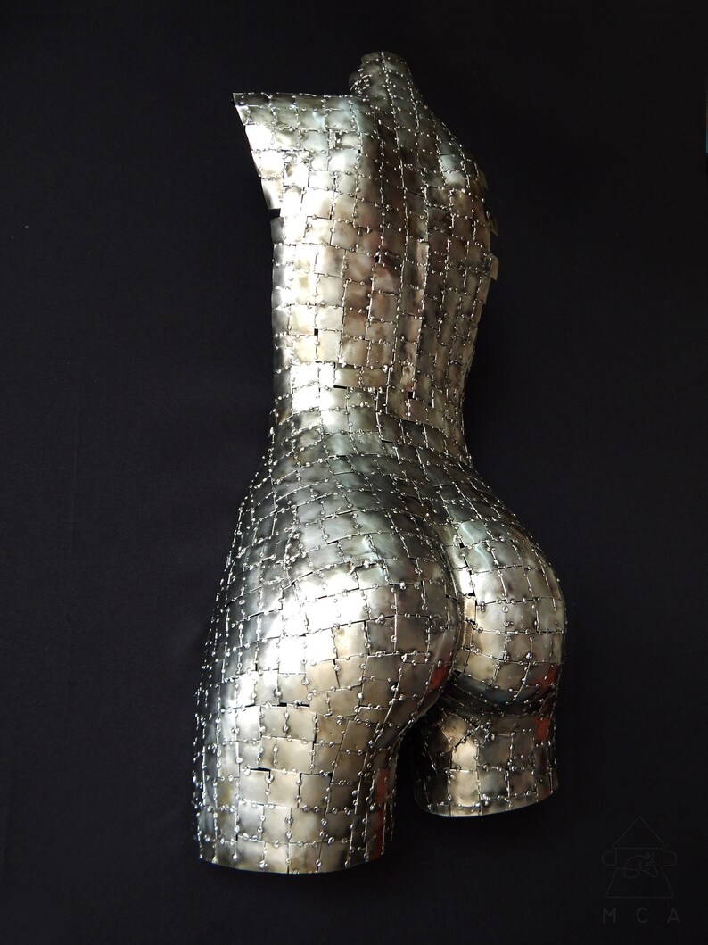 This photograph shows a metal sculpture with a female figure, made with hundreds of pieces of metal sheet that each do not exceed one inch in size, welded one by one until forming the beautiful hips of a woman and part of your back