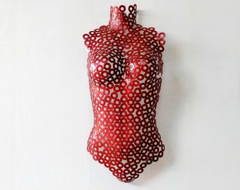 May include: Red metal sculpture of a torso made from small circles.