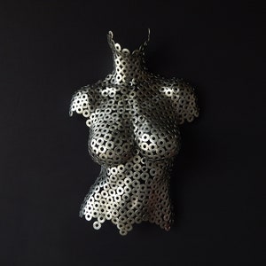 May include: A silver metal sculpture of a torso made from hundreds of small metal washers.