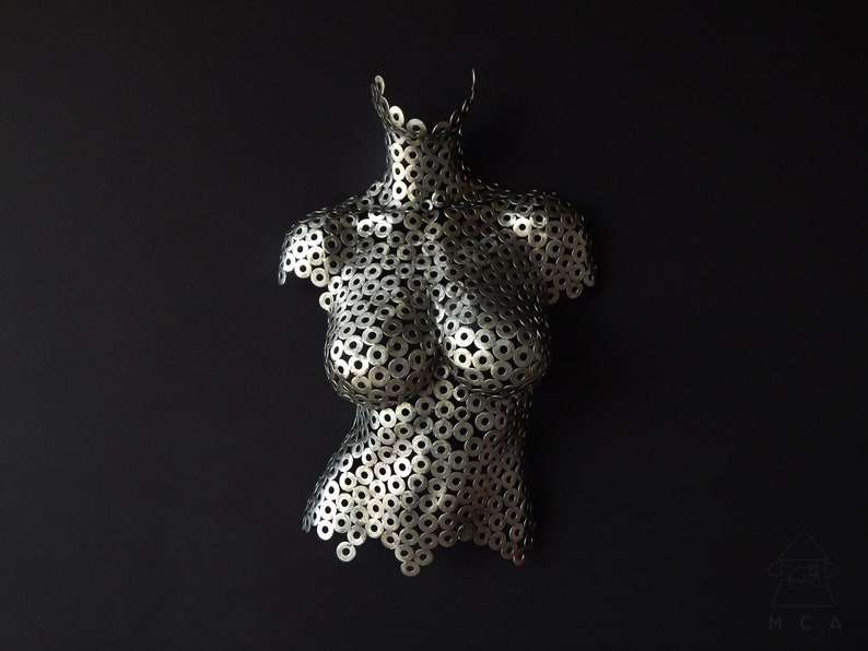 May include: A silver metal sculpture of a torso made from hundreds of small metal washers.
