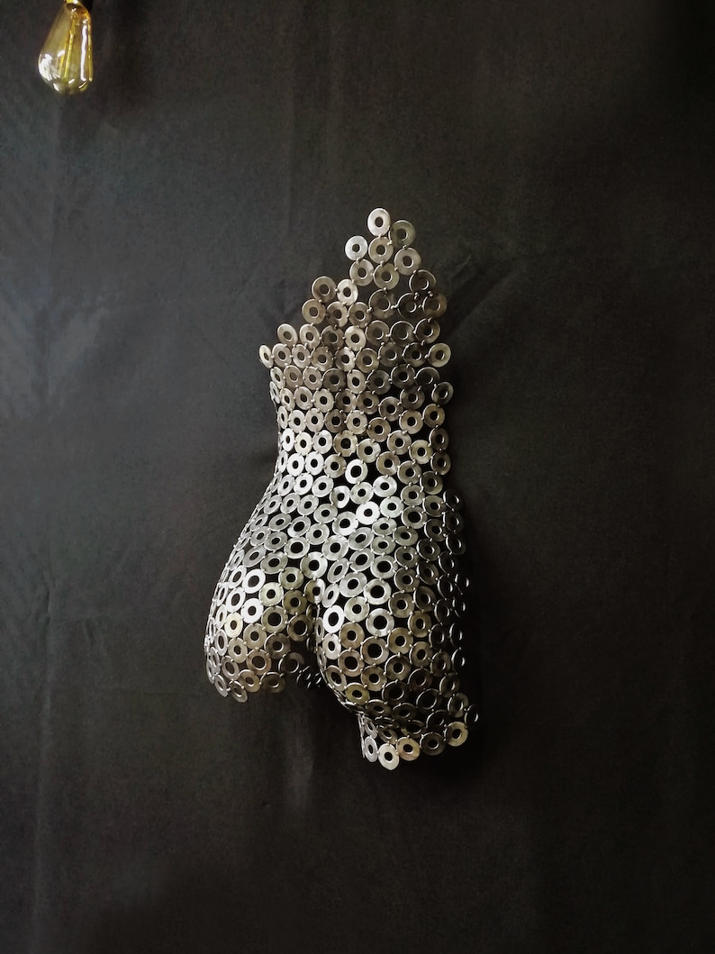 May include: A silver metal sculpture of a human torso made from many small metal washers.