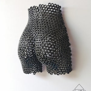 May include: A black metal sculpture of a human form made from hexagonal nuts.