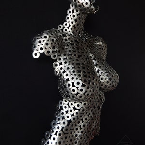 May include: A silver metal sculpture of a torso made from hundreds of small metal washers.