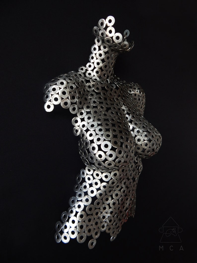 May include: A silver metal sculpture of a torso made from hundreds of small metal washers.