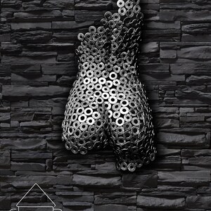May include: A metal sculpture of a human torso made from a collection of silver metal washers. The sculpture is mounted on a black brick wall.