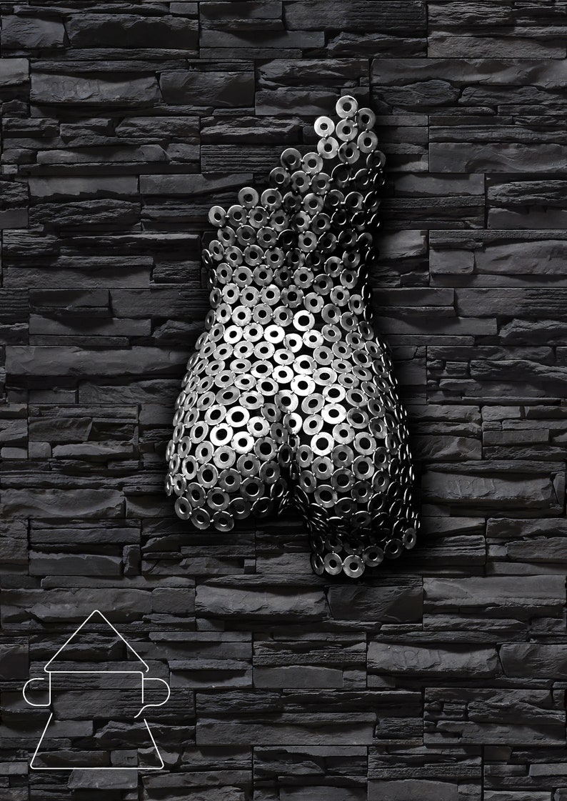 May include: A metal sculpture of a human torso made from a collection of silver metal washers. The sculpture is mounted on a black brick wall.
