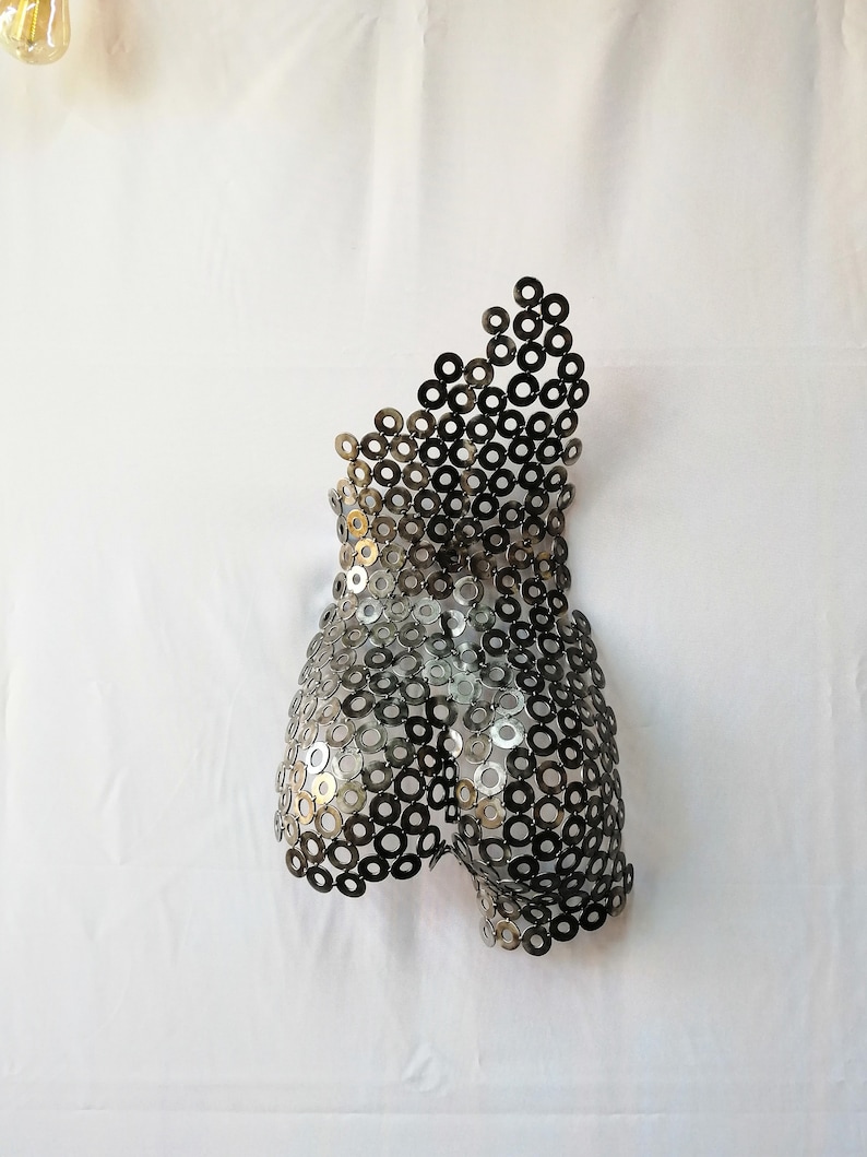 May include: A metal sculpture of a human torso made from hundreds of small, silver-colored metal rings.