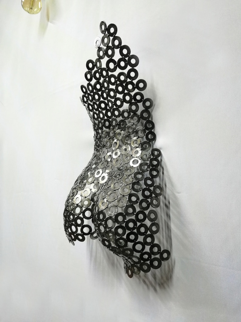 May include: A silver metal sculpture of a torso made from a series of interlocking metal rings.