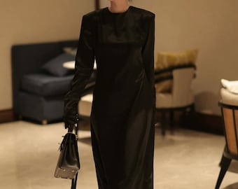 以下が含まれることがあります： 長袖とハイネックの黒いロングドレス。 ドレスには黒いハンドバッグと黒いヒールが合わせられています。 ドレスは滑らかでサテンのような外観で、体に合ったフィット感があります。