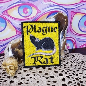 Pode incluir: Um remendo bordado amarelo com um rato preto e o texto "Plague Rat" em preto.
