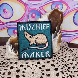 Puede incluir: Un parche bordado verde y blanco con una rata de dibujos animados y el texto "MISCHIEF MAKER".