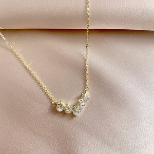 May include: A gold necklace with a delicate chain and a pendant that spells out "HAPPY" in small, sparkling letters.