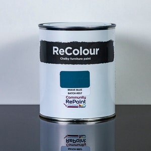 May include: A can of ReColour chalky furniture paint in the colour Brave Blue, batch number 957. The can is white with black text and a blue paint swatch. The text on the can reads "ReColour Chalky furniture paint" and "Community RePaint".