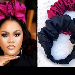 May include: Two satin headbands, one in a deep burgundy color and the other in black. Both headbands are made of soft, gathered fabric and are designed to be worn around the head.