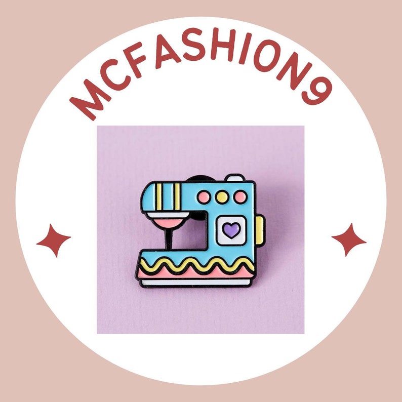 May include: A blue and yellow enamel pin shaped like a sewing machine with a pink heart on the side. The pin is on a purple background. The text "MCFASHION9" is in red letters on a white circle.