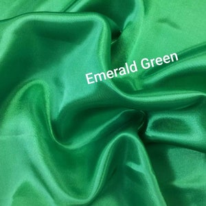 May include: Emerald green satin fabric. The fabric is smooth and silky.