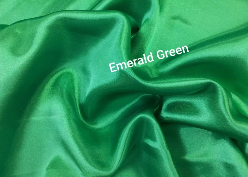 May include: Emerald green satin fabric. The fabric is smooth and silky.
