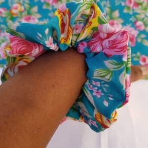Pu&ograve; includere: Un elastico per capelli in tessuto floreale blu e bianco con fiori rosa e gialli.