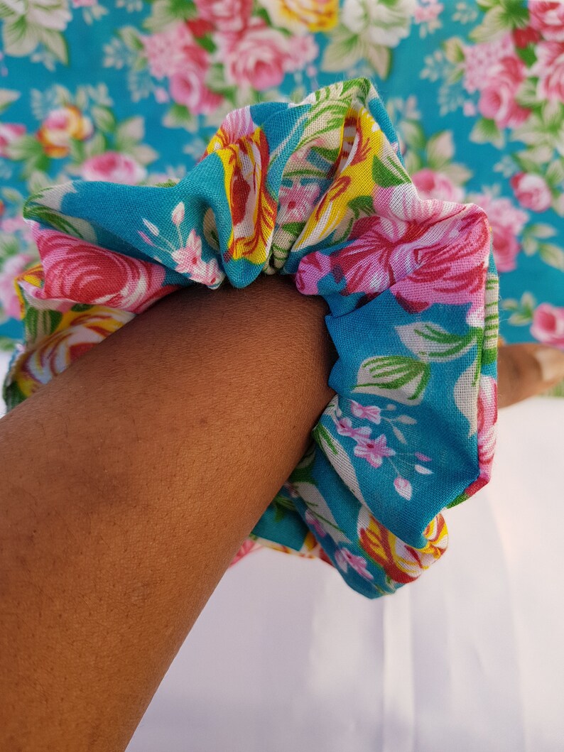 Pu&ograve; includere: Un elastico per capelli in tessuto floreale blu e bianco con fiori rosa e gialli.