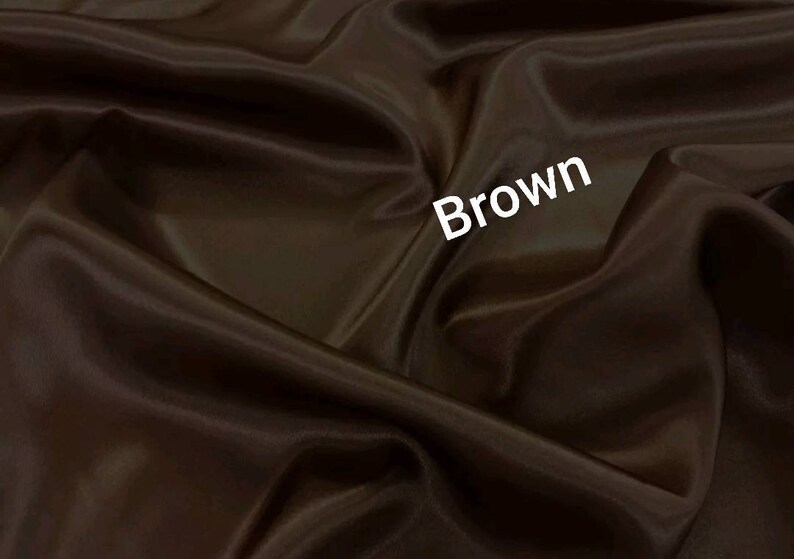 May include: A close-up of a smooth, brown fabric with a subtle sheen. The fabric is draped and folded, creating soft curves and folds. The word "Brown" is written in white text on the fabric.