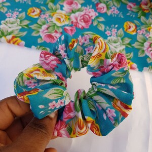 Pu&ograve; includere: Un elastico per capelli con motivo floreale blu e bianco. L'elastico &egrave; realizzato in tessuto e ha un aspetto raccolto.