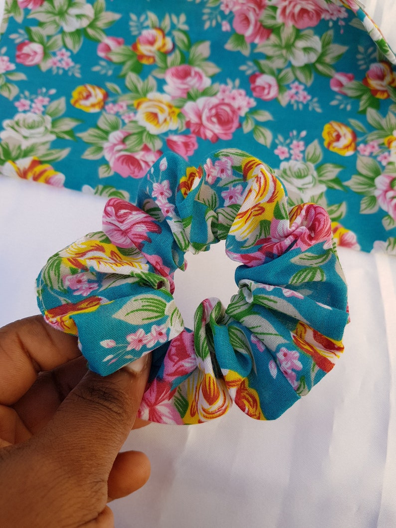 Pu&ograve; includere: Un elastico per capelli con motivo floreale blu e bianco. L'elastico &egrave; realizzato in tessuto e ha un aspetto raccolto.