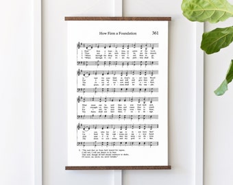 May include: A vintage-style print of a hymn sheet with the title "How Firm a Foundation" and the hymn number 361. The sheet music is printed in black and white on a white background. The print is framed with a brown wood frame.
