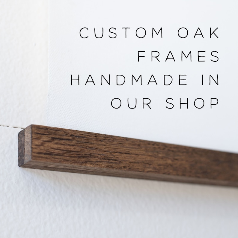 May include: A close-up of a dark brown wood frame with the text "CUSTOM OAK FRAMES HANDMADE IN OUR SHOP" printed on a white background.