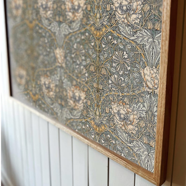 Op de afbeelding: Een ingelijste print van een vintage bloemenpatroon in tinten groen, geel en wit. De print is in een natuurlijke houten lijst.