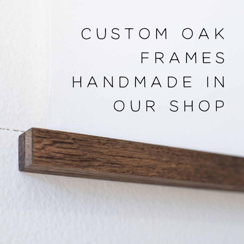 Puede incluir: Primer plano de un marco de madera marr&oacute;n oscuro con el texto "CUSTOM OAK FRAMES HANDMADE IN OUR SHOP" impreso sobre un fondo blanco.