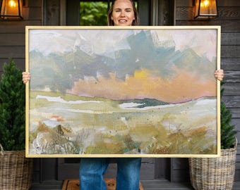 Pode incluir: Uma grande pintura de paisagem retangular numa moldura dourada fina com pinceladas abstratas em tons de verde sálvia, amarelo suave, rosa claro e creme. A obra de arte retrata uma linha do horizonte com cores em camadas e textura.