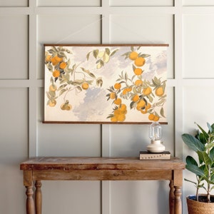 May include: A framed print of a watercolor painting depicting a branch of orange trees with ripe fruit against a light blue and white background.