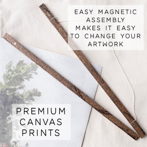 May include: Two wooden rods with magnetic ends, a white string, and a canvas print with a watercolor painting of a tree. The text "EASY MAGNETIC ASSEMBLY MAKES IT EASY TO CHANGE YOUR ARTWORK" is printed above the rods. The text "PREMIUM CANVAS PRINTS" is printed below the canvas print.
