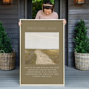 May include: A framed print with a beige background and a picture of a dirt road leading into a field. The text "PROVERBS 3:5-6" is at the top of the print. The text below the picture reads "TRUST IN THE LORD WITH ALL YOUR HEART, AND DO NOT LEAN ON YOUR OWN UNDERSTANDING. IN ALL YOUR WAYS ACKNOWLEDGE HIM, AND HE WILL MAKE STRAIGHT YOUR PATHS."