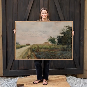 May include: A framed landscape painting with a dirt road leading into the distance. The artwork features a muted color palette with a cloudy sky and fields. The frame is a light brown color. Text from Psalm 16:11 is visible in the upper left corner.